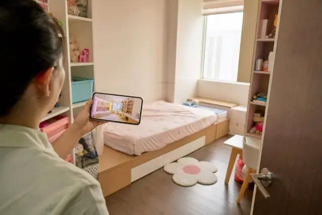 Phòng ngủ trẻ em sáng với giường đơn, đồ chơi gọn và phụ huynh xem phối cảnh do AI thiết kế trên điện thoại
